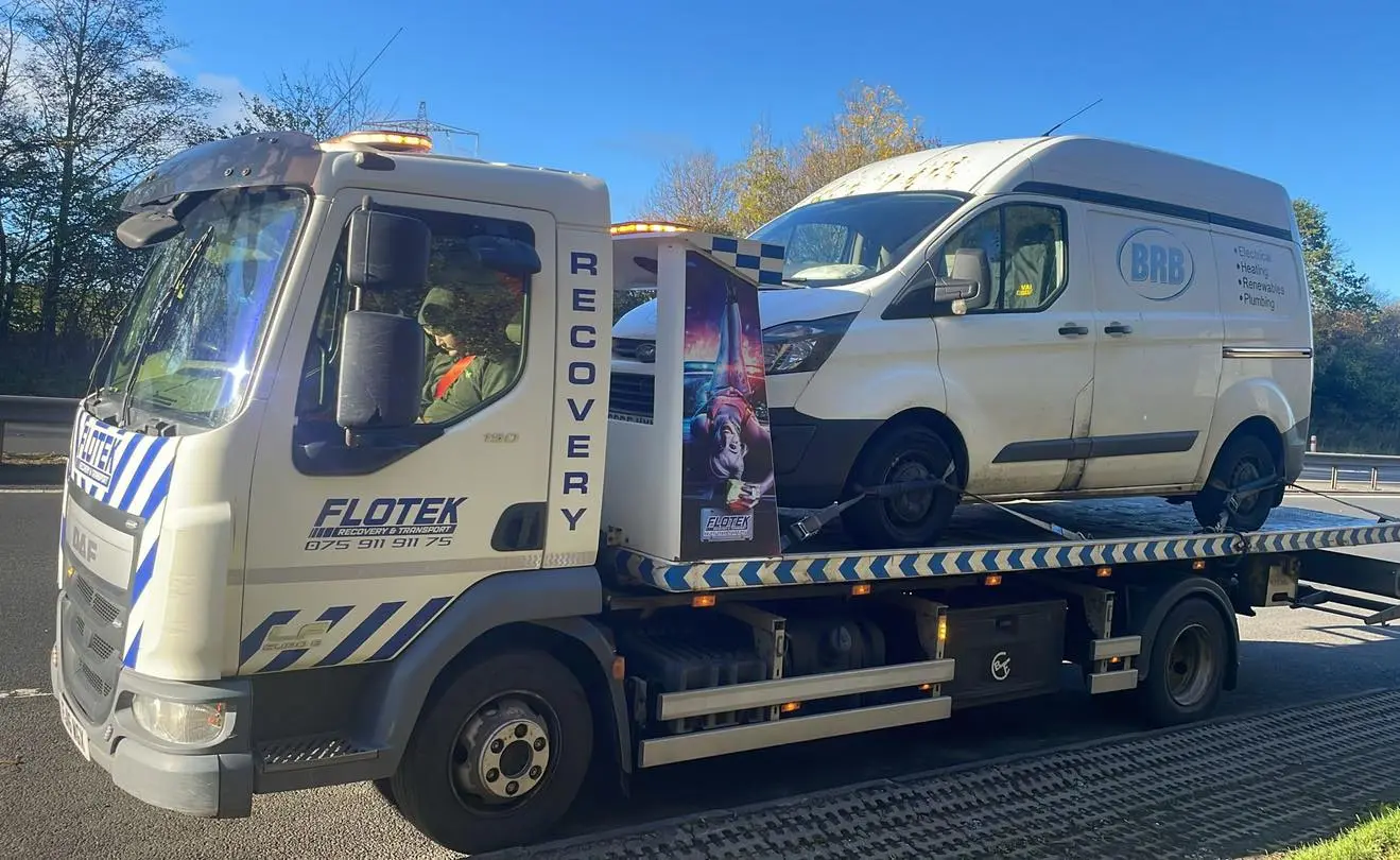 Flotek recovery truck transporting a white commercial van